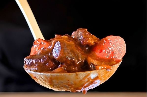 a serving spoon filled with beef bourguignon